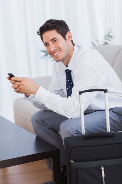 Happy businessman with suitcase and mobile phone