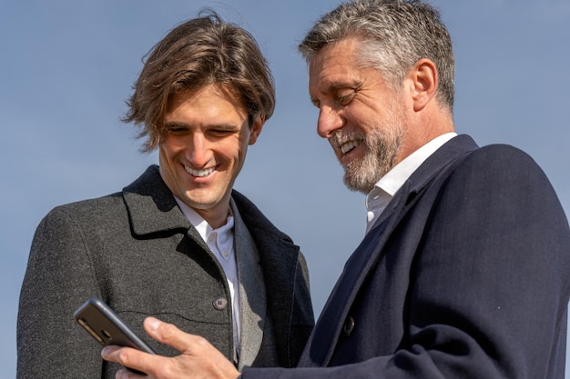 Happy businessmen using smartphone together