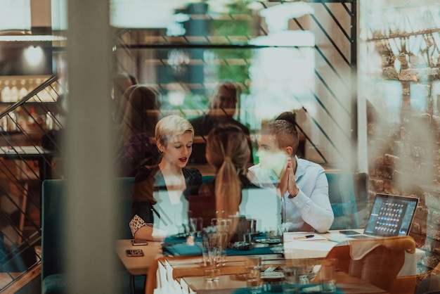 Happy businesspeople smiling cheerfully during a meeting in a coffee shop Group of successful business professionals working as a team in a multicultural workplace