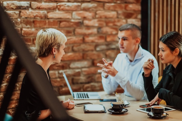 Happy businesspeople smiling cheerfully during a meeting in a coffee shop Group of successful business professionals working as a team in a multicultural workplace