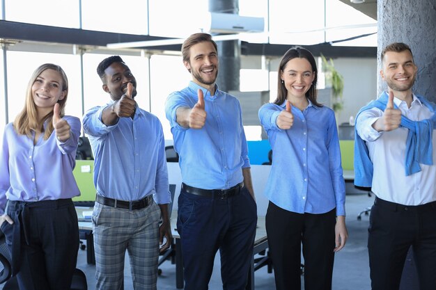 Photo happy businesspeople standing in office showing thumb up.