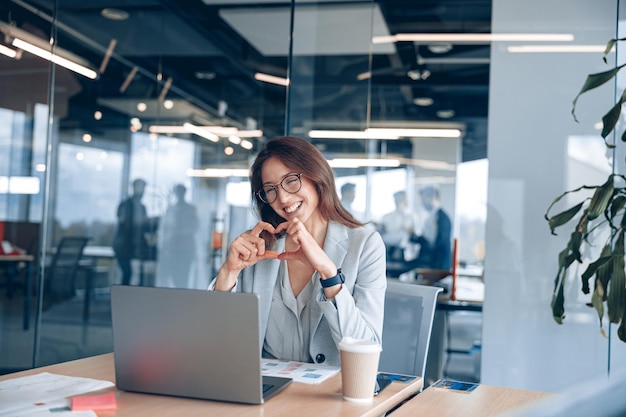 Happy businesswoman communicating in video call with friends during lunch break at modern office