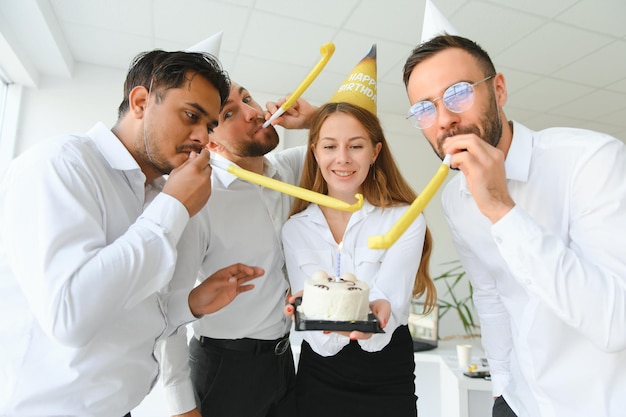 Happy businesswoman holding Birthday cake while making surprise party with her colleagues in the office