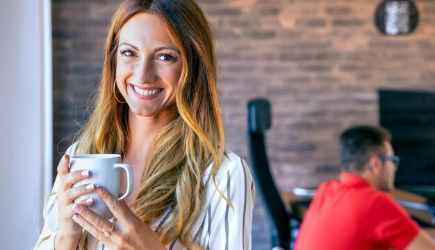 一杯のコーヒーでカメラを見て幸せな実業家