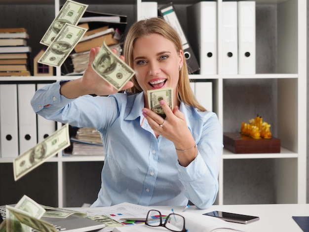 Happy businesswoman in the office throws up dollars