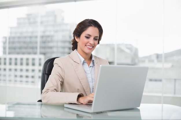 Happy businesswoman typing on laptop at her desk