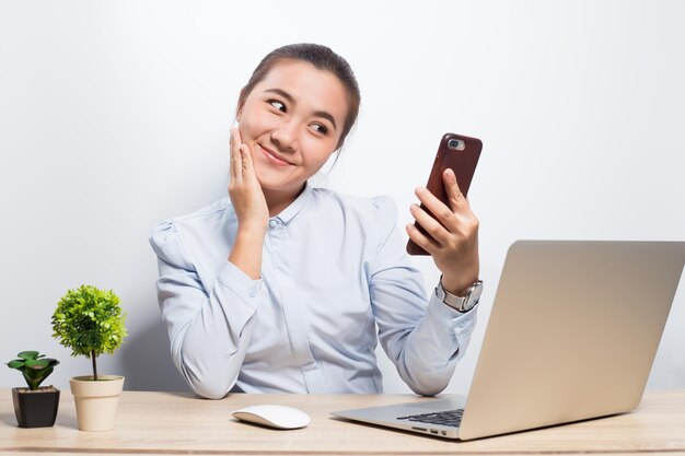 Happy businesswoman using mobile phone while sitting in office