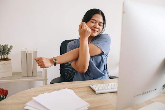 Happy businesswoman warming up body and muscles at workplace