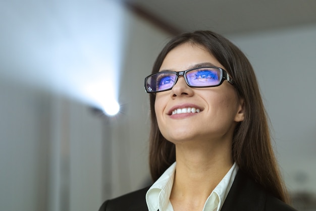 The happy businesswoman with glasses on the background of projector