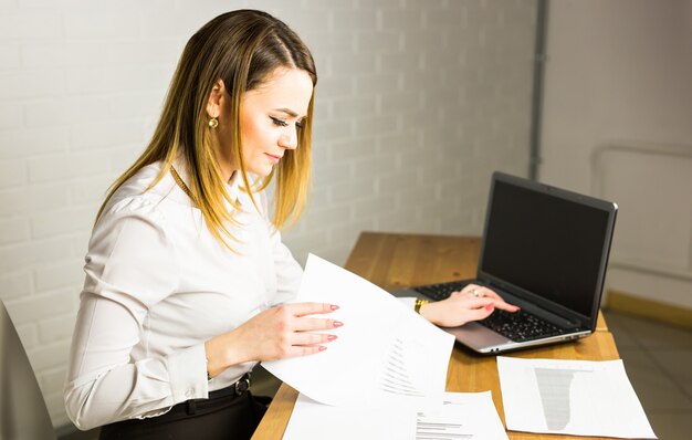 オフィスでラップトップに取り組んで幸せな女性実業家