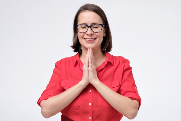 Il responsabile femminile riconoscente calmo felice unisce le mani che pregano sorridere.