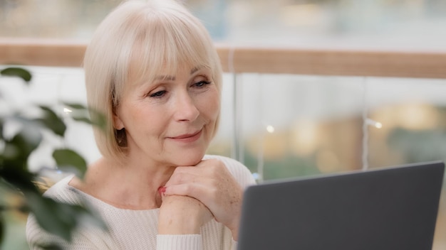 Happy calm mature middle aged woman sitting resting relaxing holding hands under chin looking at