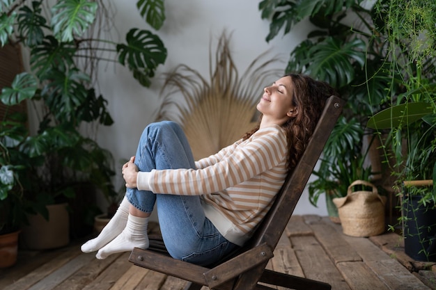 Foto felice calma donna pacifica che sogna con gli occhi chiusi e sorriso sul viso in serra tropicale