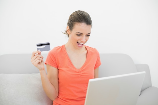 Acquisto domestico della donna calmo felice con il suo computer portatile