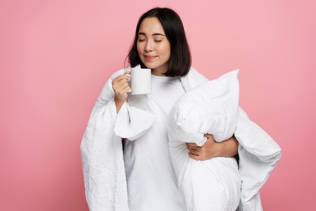 Happy calm woman hugging pillow and drinking morning coffee