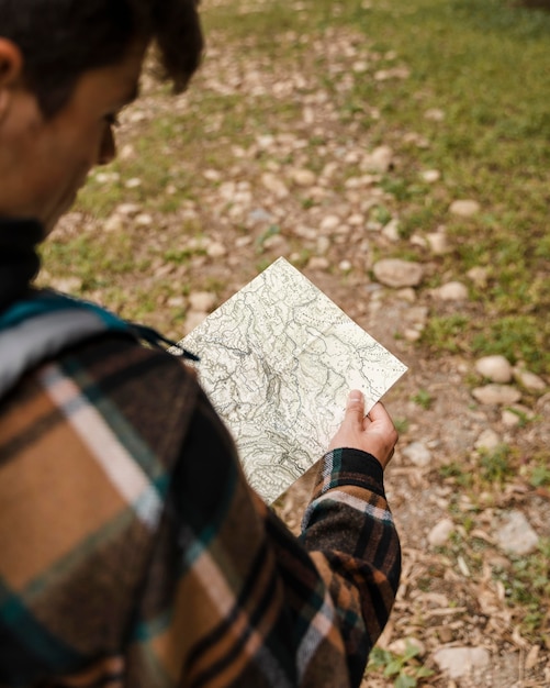 Foto uomo di campeggio felice nella foresta che osserva sulla mappa