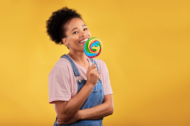 Happy candy and portrait of a black woman with a lollipop on a studio background for food smile mockup and an african girl or model with sweets for dessert isolated on a backdrop with space