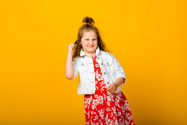 Happy carefree child emotions. Energetic joyful adorable little girl laughing at joke on yellow background in studio.