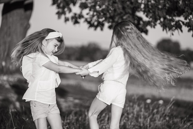 Photo happy and carefree childhood two girls in white clothes are circling joyful and happy children hold hands children39s games in the village