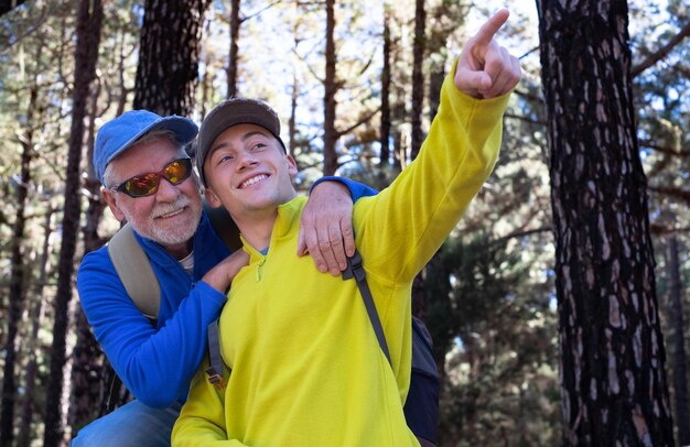 Happy and carefree couple of grandfather and teenager grandson hiking in the mountains sharing same passion for nature and healthy lifestyle together in the woods Adventureisageless