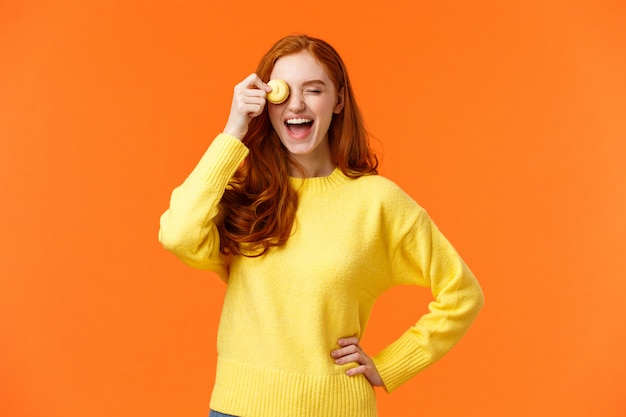 Happy and carefree smiling, laughing lovely redhead girl grinning, holding tasty macron