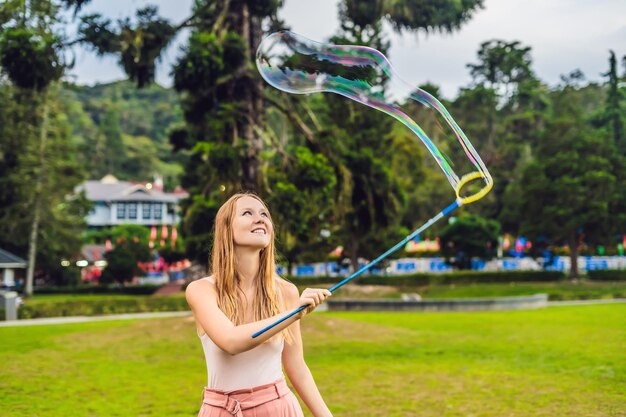 Happy carefree young woman blowing soap bubbles