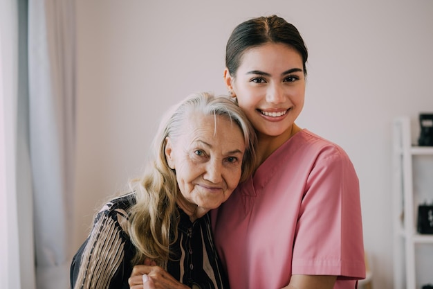 Photo happy caregiver and senior patient smiling and looking at camera senior woman and doctor at home