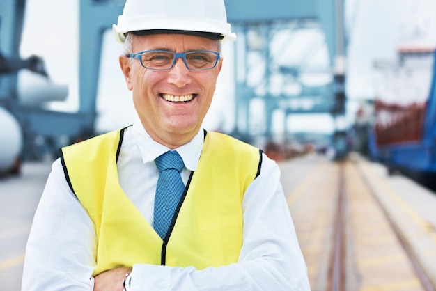 Happy cargo logistics and shipping manager smile on a port with a factory warehouse or plant in the background Manufacturing supply chain and freight leader in the industrial delivery business