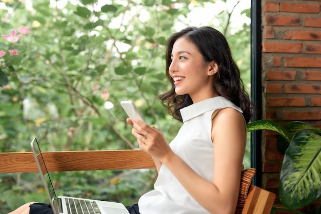 Happy casual beautiful woman is talking on a phone sitting on a sofa at home.