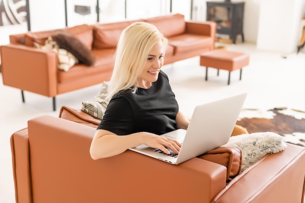 Happy casual beautiful woman working on a laptop sitting in the house.