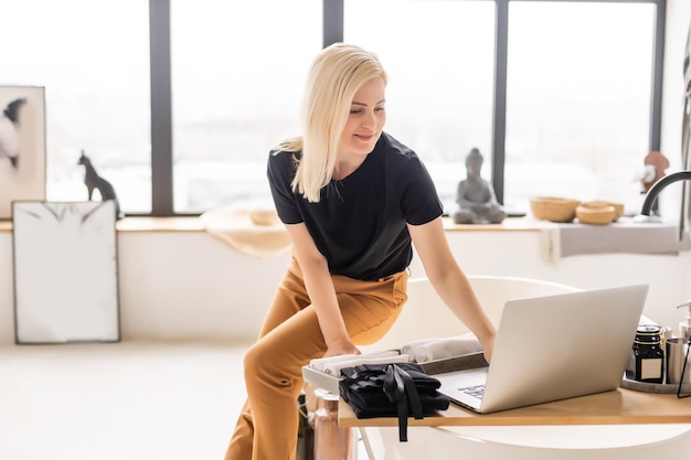 Happy casual beautiful woman working on a laptop sitting in the house.