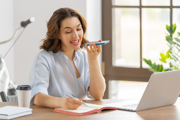 Happy casual beautiful woman working on a laptop and talking by phone in the office