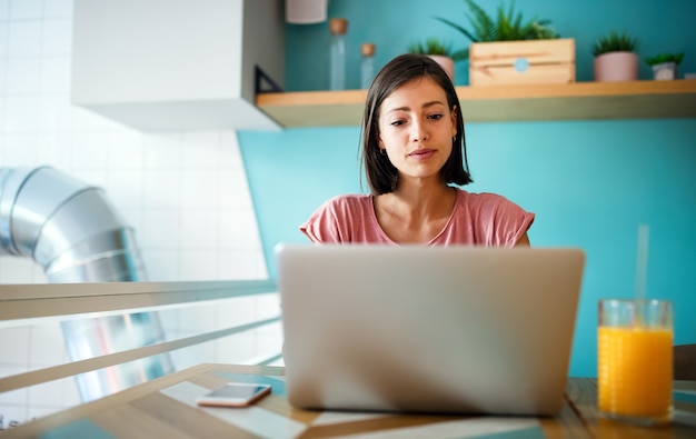 Felice bella donna casual che lavora, studia, fa surf, fa shopping su un laptop