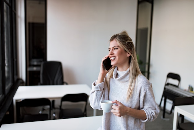 Happy casual businesswoman talking on the phone on the coffee break.