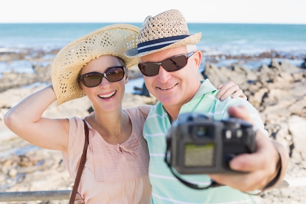 Happy casual couple taking a selfie by the coast