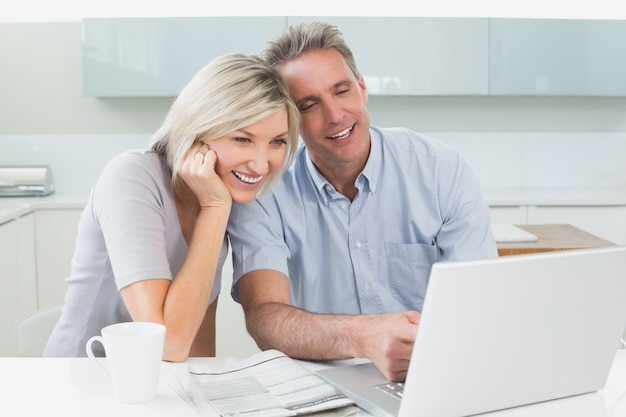 Happy casual couple using laptop in kitchen