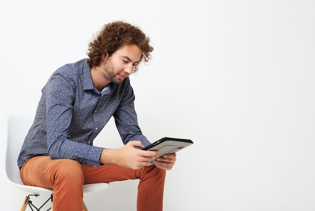 タブレットPCと椅子の上の幸せなカジュアルな男