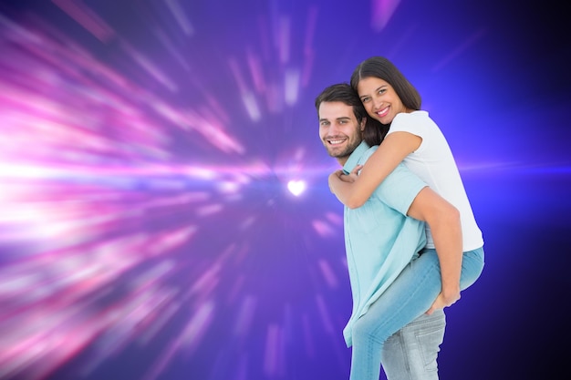 Happy casual man giving pretty girlfriend piggy back against valentines heart design