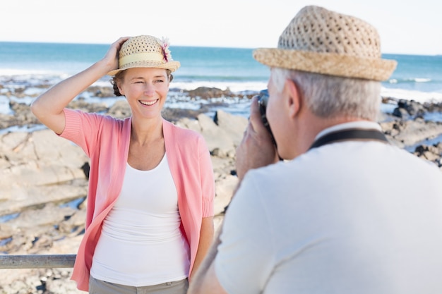 Happy casual man taking a photo of partner by the sea