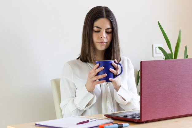 写真 在宅勤務幸せなカジュアルな女性。手にコーヒーを入れて。