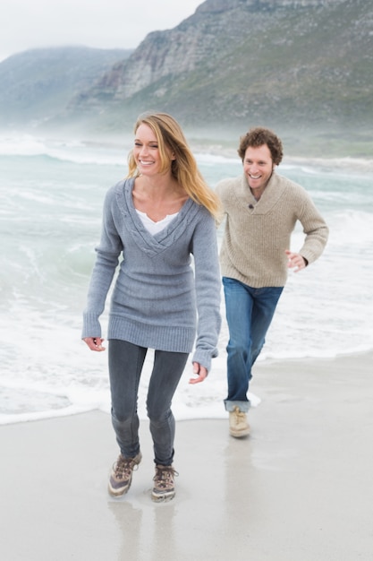 Happy casual young couple running at beach