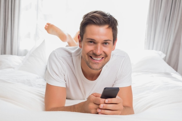 Счастливый случайный молодой человек текстовых сообщений в постели