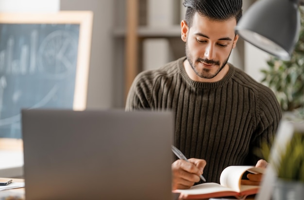 Happy casual young man working on a laptop at home.