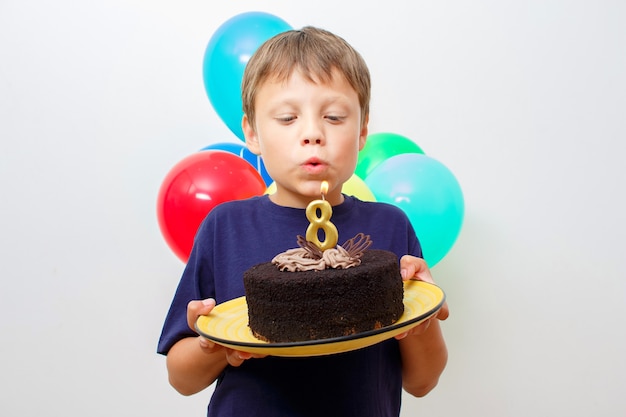 Happy caucasian boy holding a chocolate cake in his hands with candle