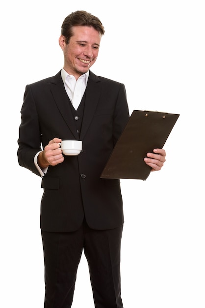 Happy Caucasian businessman reading clipboard while holding coffee