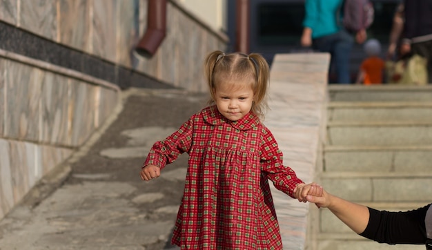 Happy caucasian child of two years old walking down holding the mother hand