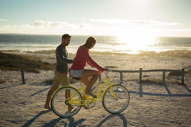 Happy caucasian couple at the sea learning to ride bicycle. healthy outdoor leisure time by the sea.