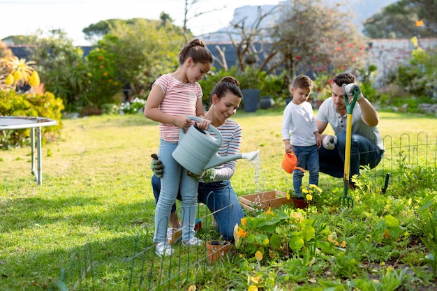 Happy caucasian family gardening and watering plants together. family time, having fun together at home and garden.