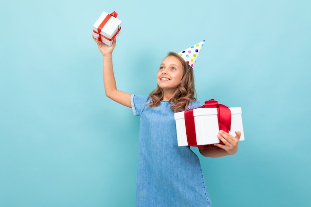 Happy caucasian girl with holiday hat holding her presents  light blue 