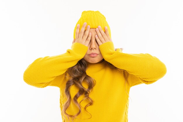 Happy caucasian girl in yellow hat and hoody closed her eyes isolated on white background